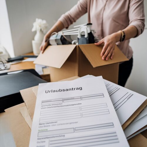 Arbeitnehmerin räumt Schreibtisch, unausgefüllter Urlaubsantrag liegt darunter