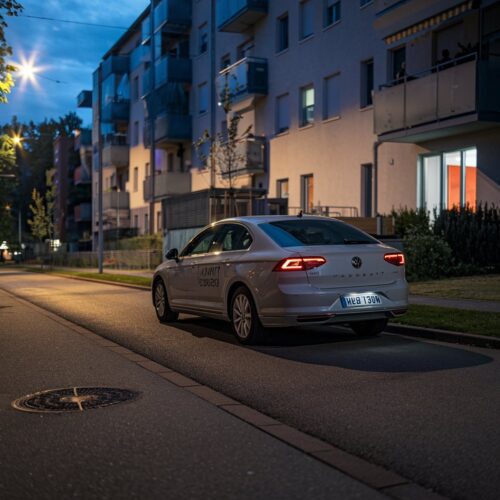 Firmenwagen steht am Abend vor einem modernen Wohnhaus in einer ruhigen Straße.